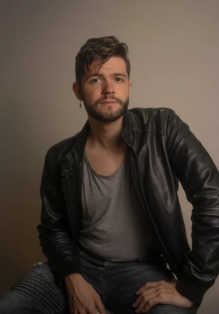 Un jeune homme avec une boucle d'oreille en forme de plume, et une veste en cuir.